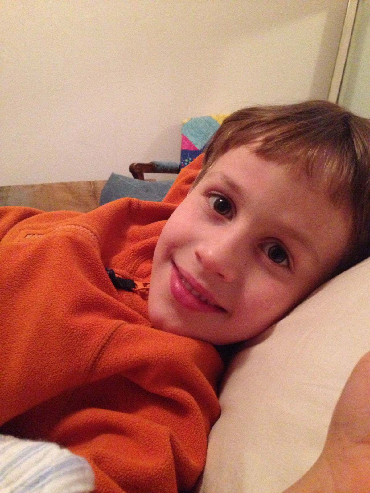 A boy laying on the bed, looking at the camera
