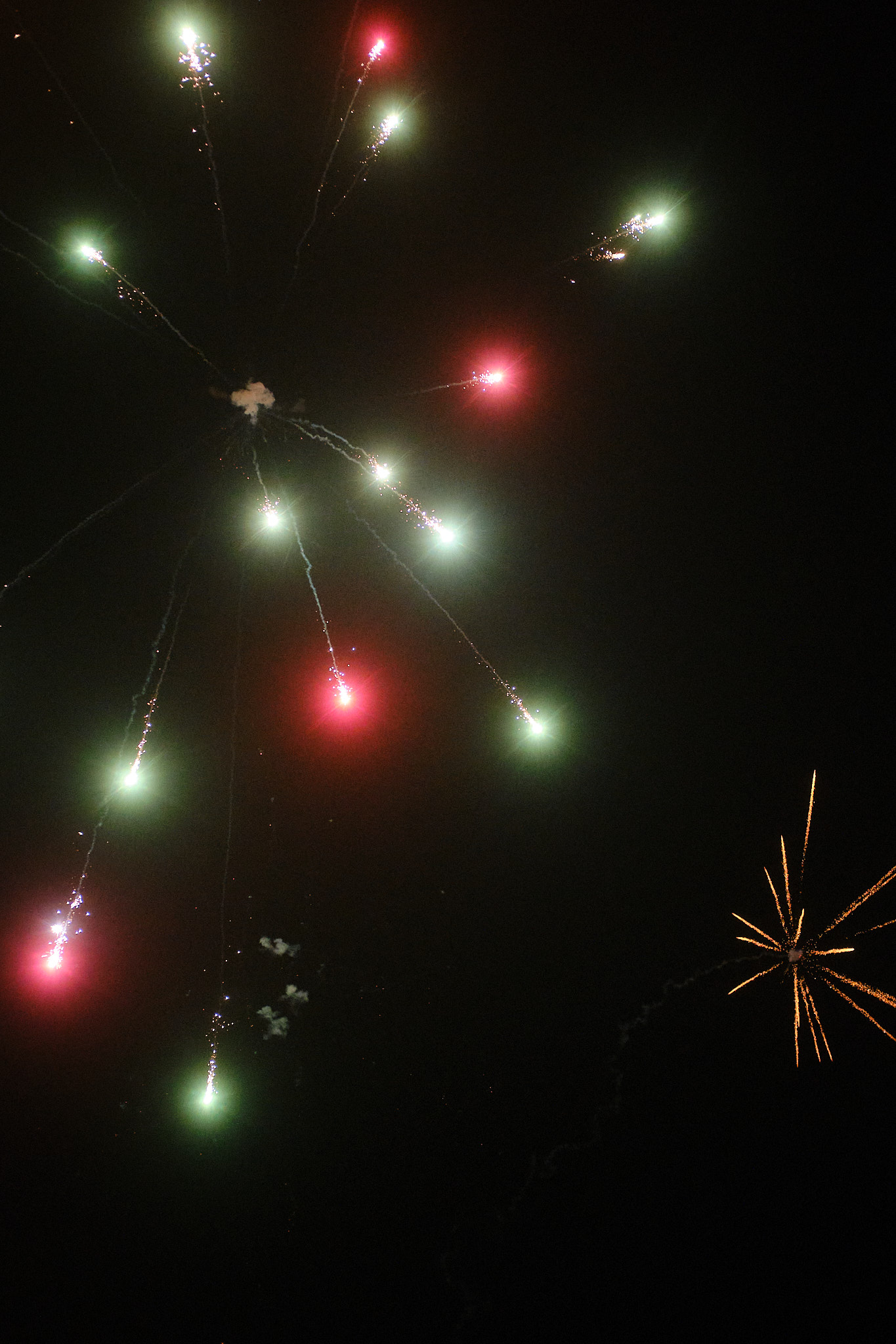red and green fireworks in a pitch black sky
