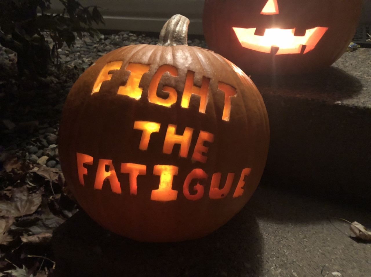 A lit pumpkin, carved with the words “Fight the Fatigue”