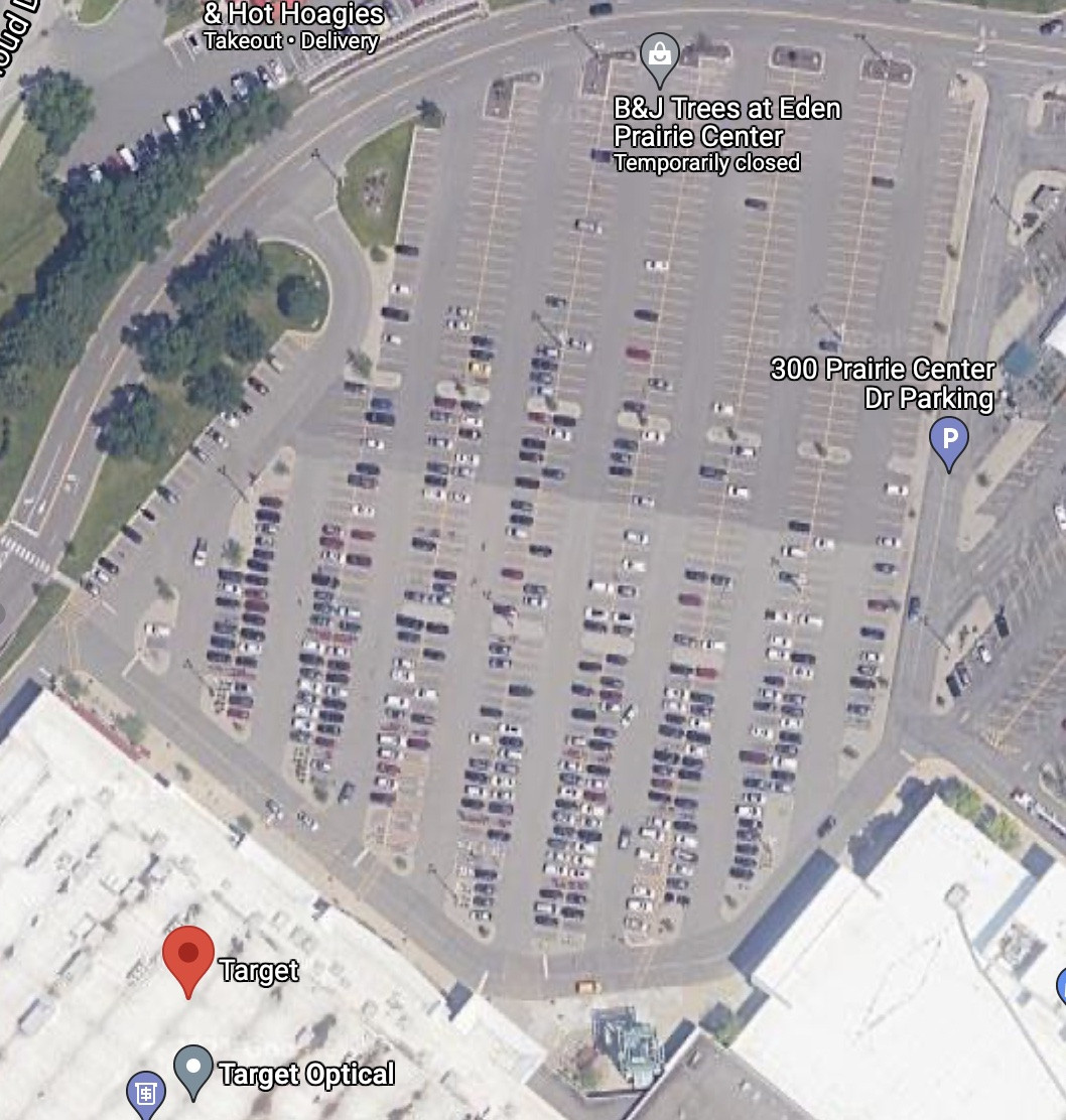 An aerial view of a large parking lot near a target store, with only a few very long rows for cars