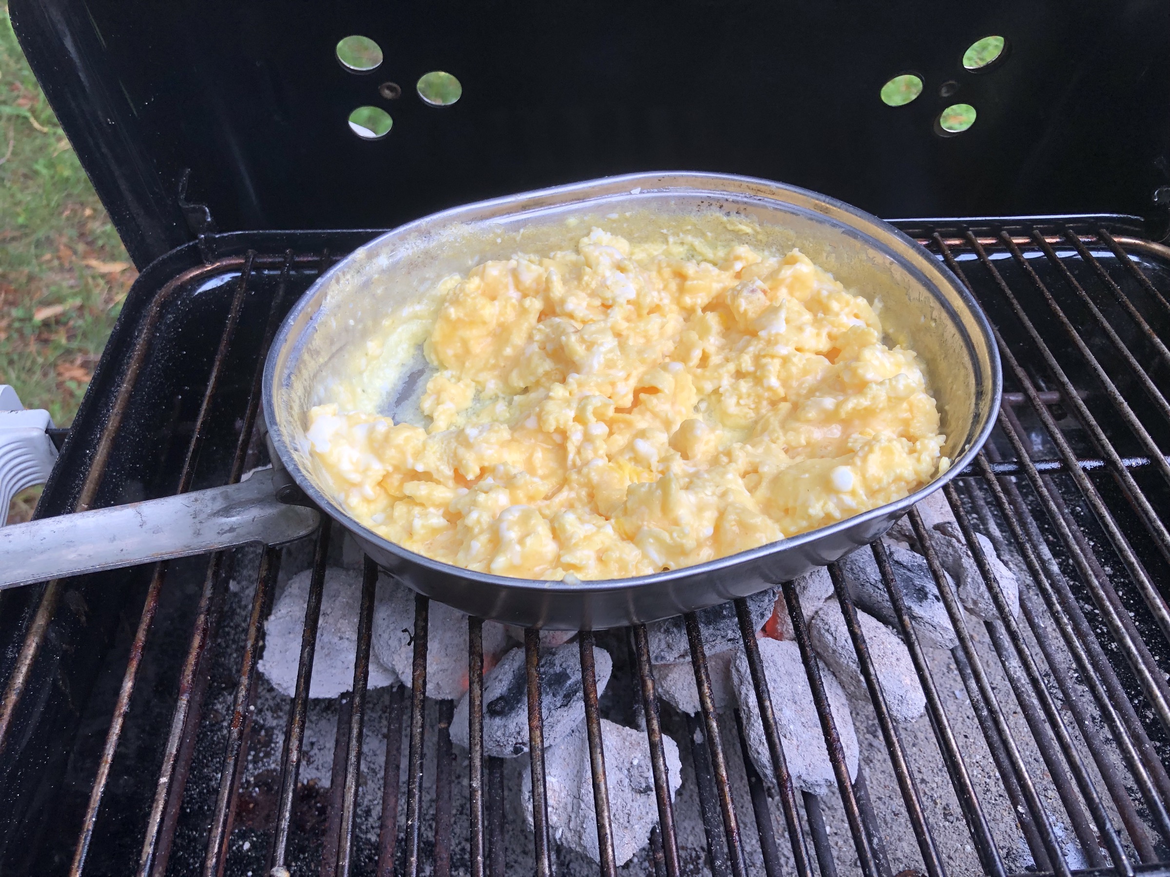 A folding camping frying pan with perfectly cooked scrambled eggs