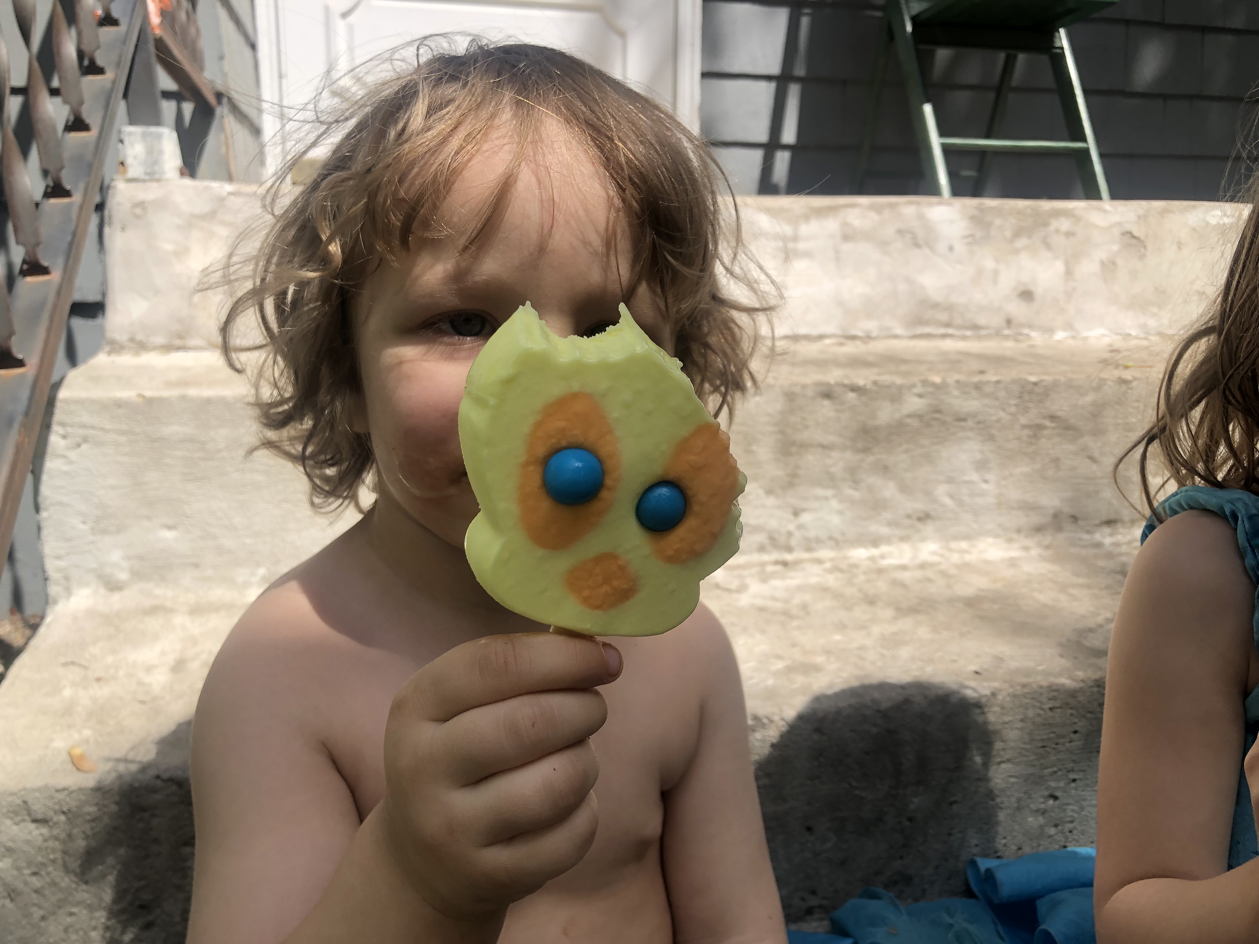 Toddler holding a partially eaten tweety bird popsicle in front of their face